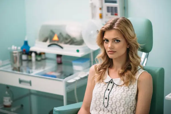 stock image A young woman with wavy hair waits calmly in a dental clinic, surrounded by dental equipment and a peaceful ambiance.