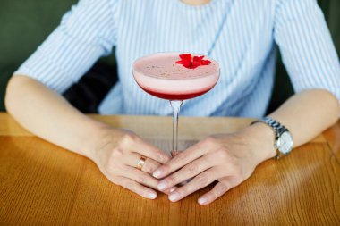 Kafede kokkuyruk içen çekici genç bir kadının portresi.