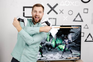 Genç adam evde vakit geçiriyor, kanepede oturuyor ve konsolda video oyunları oynuyor. Oyun oynamak ve kazanmak için joystick kullanan başarılı bir erkek.