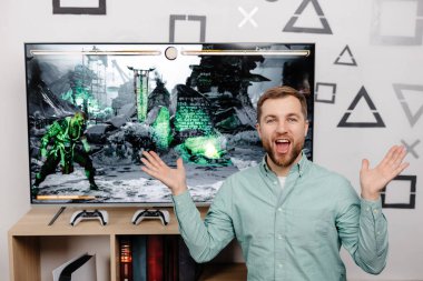 Genç adam evde vakit geçiriyor, kanepede oturuyor ve konsolda video oyunları oynuyor. Oyun oynamak ve kazanmak için joystick kullanan başarılı bir erkek.