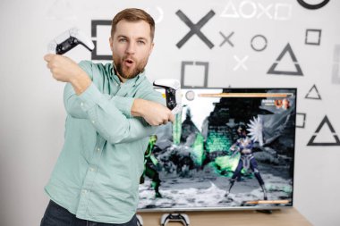 Genç adam evde vakit geçiriyor, kanepede oturuyor ve konsolda video oyunları oynuyor. Oyun oynamak ve kazanmak için joystick kullanan başarılı bir erkek.