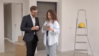 Genç tasarımcı ve müşteri işadamı, yeni oturma odasının içinde dijital tabletle birlikte iç mekan tasarımı yapıyor.