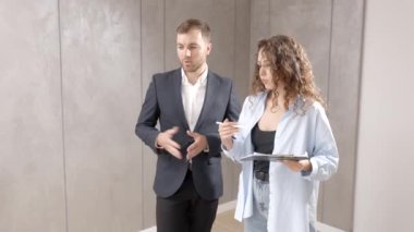 Genç bir tasarımcı müşteriyle odanın planlarını ve tasarımını tartışır. Modern bir tasarımda tamir kavramı