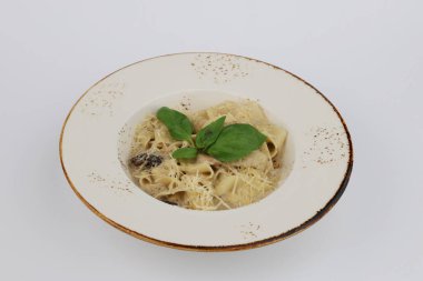 Beyaz arka planda beyaz bir tabakta krema soslu, tavuk ve mantarlı Fettuccine makarna..