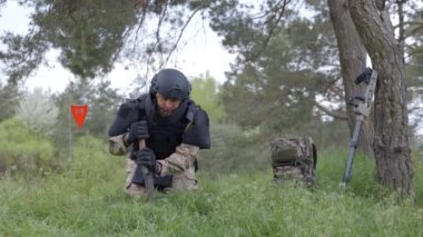 Özel takım elbiseli bir adam dedektörle çalışıyor ve patlayıcı bir cihaz buldu. Bir adam yüksek patlayıcı anti-personel basıncını etkisiz hale getirmeye çalışıyor.