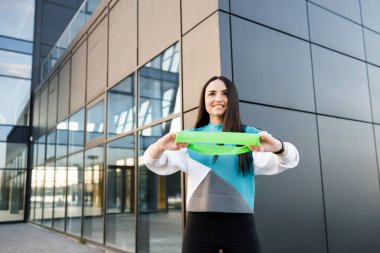 Spor salonundaki kadın dışarıda jimnastik lastiğiyle çalışıyor. Lastik genişletici ile sağlıklı kız eğitimi, sağlıklı yaşam tarzı kavramı. Fitness