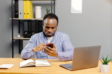 Masada oturan adam cep telefonu kullanıyor..