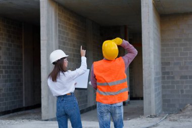 Mimar ve ustabaşı proje detaylarını bir panoda gözden geçiriyorlar, başarılı bir yapı geliştirme sağlıyorlar