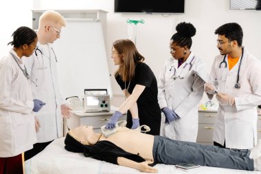 Bir grup doktor yanında dikilip tıbbi durumunu ve tedavi seçeneklerini tartışırken bir kadın yatakta uzanıyor..