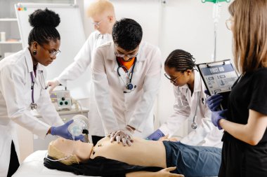 Bir grup beyaz önlüklü doktor, muayene masasında oturan bir hastanın etrafını sardı..