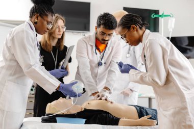 Bir grup beyaz önlüklü doktor, muayene masasında oturan bir hastanın etrafını sardı..