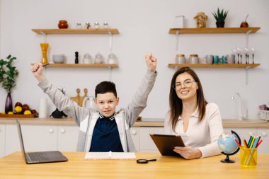 Genç bir kadın bir çocuğa tablet ve küre kullanarak derslerinde yardım ediyor. Evde eğitim gören bir öğrenci ödevini özel öğretmenin yardımıyla yapar..