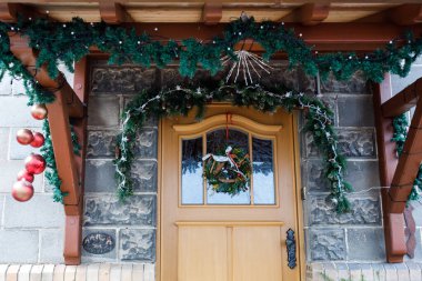 Noel süsleri, çelenkler ve fenerler ev girişinde sıcak ve davetkar bir atmosfer yaratarak tatil sezonunu kutluyorlar.