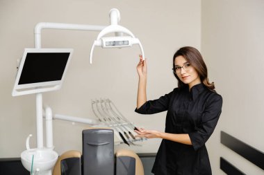 Modern klinikte genç bir dişçinin portresi. Bayan bir dişçi sizi nazikçe randevuya davet ediyor..