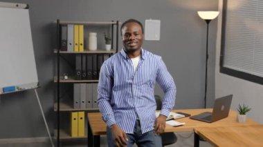 Pozitif siyah adam büro masasının yanında duruyor ve el hareketi yapıyor. İyi sonuç alabilmek için işaret ediyor.