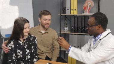 Afrikalı yönetici ofis masasında dizüstü bilgisayarın önünde oturuyor ve keyifli bir telefon görüşmesi yapıyor..