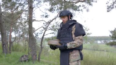 Özel takım elbiseli bir adam dedektörle çalışıyor ve patlayıcı bir cihaz buldu. Adamın biri tanksavar mayınını etkisiz hale getirmeye çalışıyor.