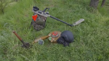 Patlayıcı cihazlar ve metal detektörü bir orman kitlesinin arka planında bulunur. Bölgenin mayınlarını temizleme ekipmanı