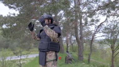 Üniformalı ve taktik yelekli genç asker ormanda çalışıyor ve geçici bir orman üssünde harekete geçmeye hazırlanıyor. Mayınlardan kurtulmak için sıkı çalıştıktan sonra bir adam koruyucu kaskını çıkarır.