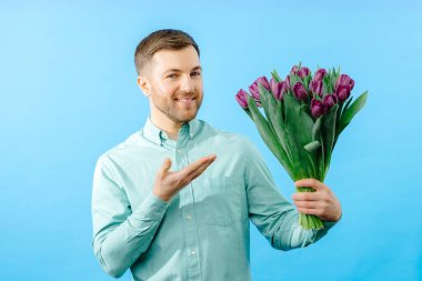 Adamın elinde koyu arkaplanda mor lalelerden oluşan bir buket var. Anneler Günü için bahar çiçekleri, Uluslararası Kadınlar Günü, doğum günü.
