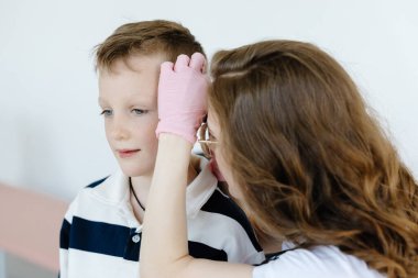 Ofiste otoskopla çocuğun kulağını inceleyen kadın doktor. Kulak boşluğu sağlık kontrolü.