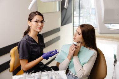 Diş muayenesi yapılırken acı ve endişe çeken genç bir kadın..