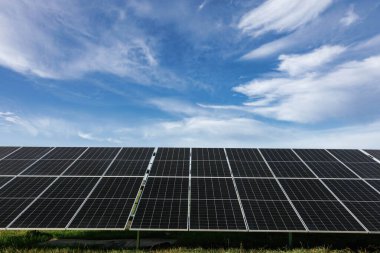 Güneş panelleri, mavi gökyüzü altında güneş ışığını emerek, yenilenebilir enerji ve sürdürülebilirliği sembolize ediyor.