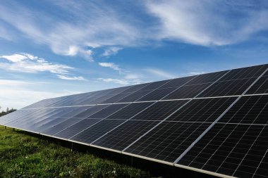 Güneş panelleri, mavi gökyüzü altında güneş ışığını emerek, yenilenebilir enerji ve sürdürülebilirliği sembolize ediyor.