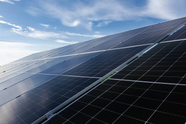 Güneş panelleri, mavi gökyüzü altında güneş ışığını emerek, yenilenebilir enerji ve sürdürülebilirliği sembolize ediyor.