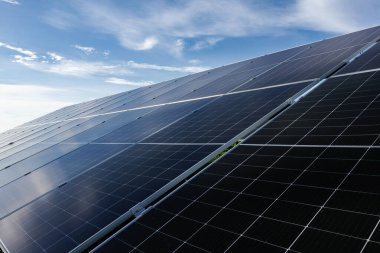 Güneş panelleri, mavi gökyüzü altında güneş ışığını emerek, yenilenebilir enerji ve sürdürülebilirliği sembolize ediyor.