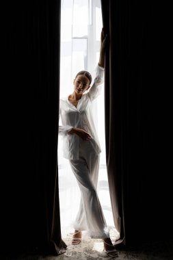 Gelin beyaz ipek pijama giyip, tüylü kelepçelerle düğün günü iki siyah perde arasında perde açıyor.