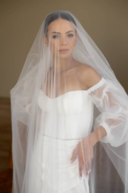 Bir fotoğraf çekimi için şık bir gelin, beyaz bir gelinlik ve duvak giyiyor, gelin modasını gözler önüne seriyor.