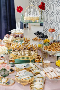 Çeşitli hamur işleri ve meyveler özel bir etkinlik için zarif bir şekilde masaya dizildi.