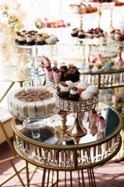 Çeşitli hamur işleri ve pastalar taze böğürtlenlerle süslenmiş cam ve altın katlı sergiler düğün resepsiyonunda