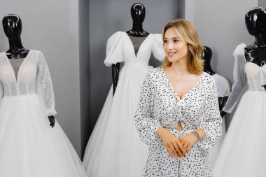 Müstakbel gelin, gelinlik almak için gelinlik salonuna geldi. Güzel bir kadın kuaförde gelinlik seçer..