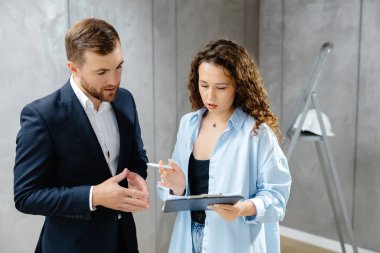 Genç bir tasarımcı müşteriyle odanın planlarını ve tasarımını tartışır. Modern bir tasarımda tamir kavramı.