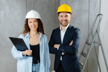 Tadilat için izin çıkarttık. Çekici genç müteahhit ve müşteri kaskla odada dikilip kameraya bakıyor..