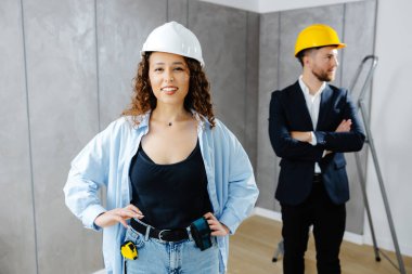 Tadilat için izin çıkarttık. Çekici genç müteahhit ve müşteri kaskla odada dikilip kameraya bakıyor..