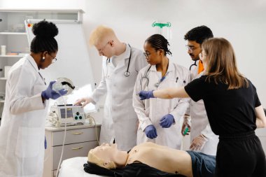 Çeşitli tıp öğrencileri bir eğitim mankeni üzerinde kardiyopulmoner canlandırma yapmayı öğreniyor.