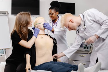 Farklı tıp öğrencileri, acil bakım simülasyonu eğitimi sırasında endotrakeal entübasyon pratiği yapıyorlar.