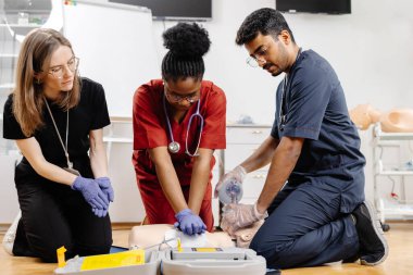Çeşitli tıp öğrencileri hastane veya klinikte ilk yardım eğitimi sırasında tıbbi mankenler üzerinde kalp masajı yapıyor.