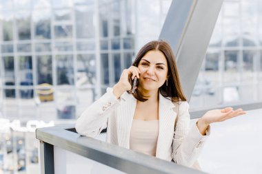 Sokakta yürürken cep telefonuyla konuşan mutlu genç bir iş kadını. Toplantıya yürüyen güzel bir kadın.