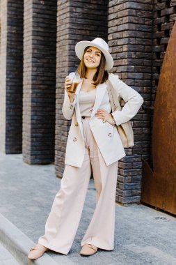 Beautiful woman going to meeting with cold coffee walking on the street. Portrait of successful business woman holding cup of cold drink in hand on her way to work on city street