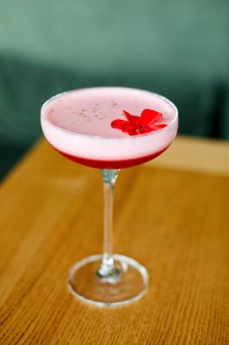 Masada duran kırmızı kokteylli bir bardak.