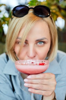 Kafede kokkuyruk içen çekici genç bir kadının portresi.