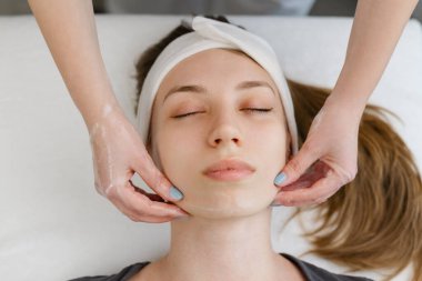 Profesyonel spa tedavisi, rahatlatıcı bir yüz masajı, cilt bakımını ve sağlığını destekliyor. Terapist, gençleşmek için müşterinin yüzüne nazikçe masaj yapıyor.