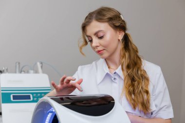 Profesyonel güzellik uzmanı, güzellik salonunda müşterinin yüzüne ışık terapisi uyguladı.