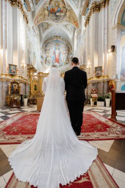 Geleneksel düğün töreninde güzel kilisede dikilen zarif gelin ve damadın dikiz manzarası