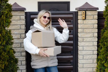 Mutlu müşteri, evinin yakınındaki teslimatçıya el sallayan iki karton kutu alıyor.