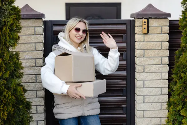 Mutlu müşteri, evinin yakınındaki teslimatçıya el sallayan iki karton kutu alıyor.